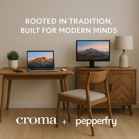 Wooden desk with laptop and monitor, chair, and lamp against a beige wall with 'croma + pepperfry' branding.
