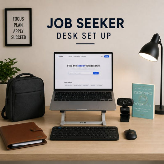 A styled desktop setup on a light wood desk with a laptop on a stand, keyboard, mouse, black backpack, lamp, webcam, notebook, and a teal book. Large wall text reads 'JOB SEEKER DESK SET UP' above the desk.